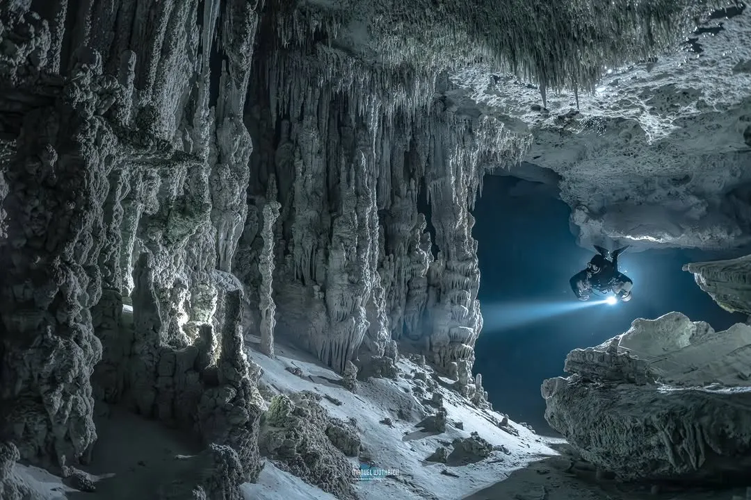 D26 cave diving in Switzerland - beam cutting through dark freshwater